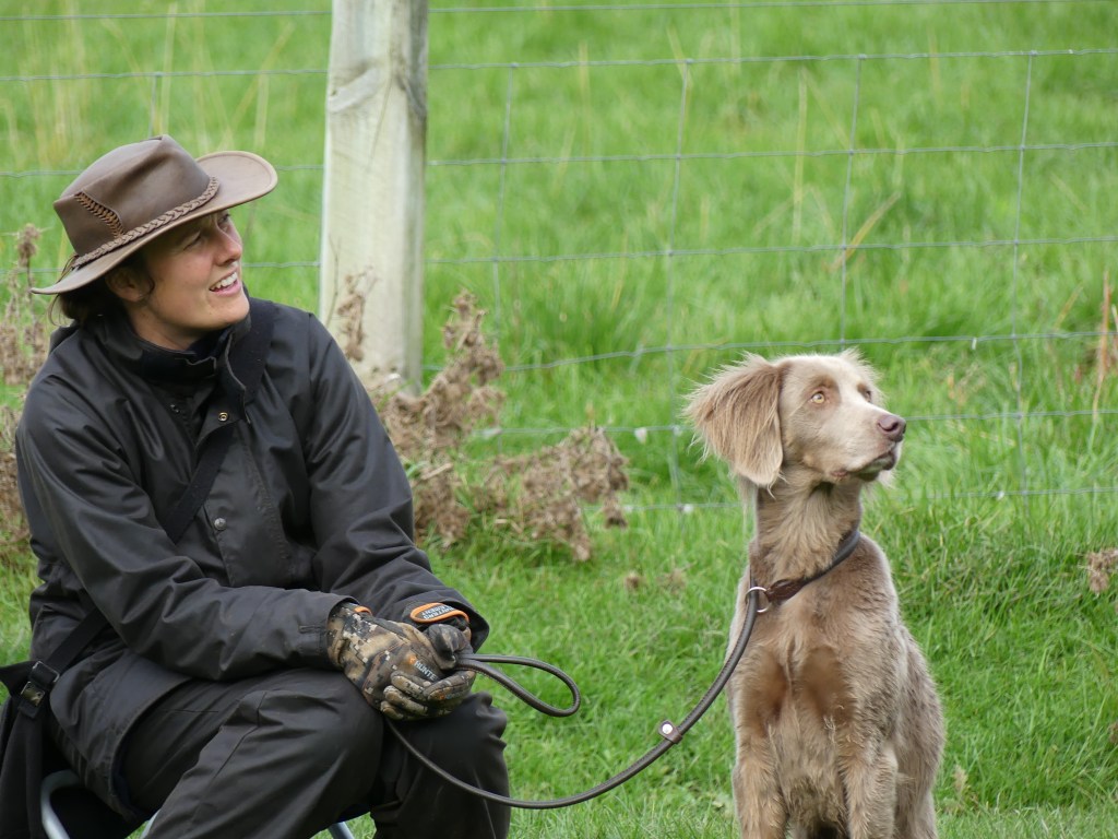 Handler in oilskins sitting with dog